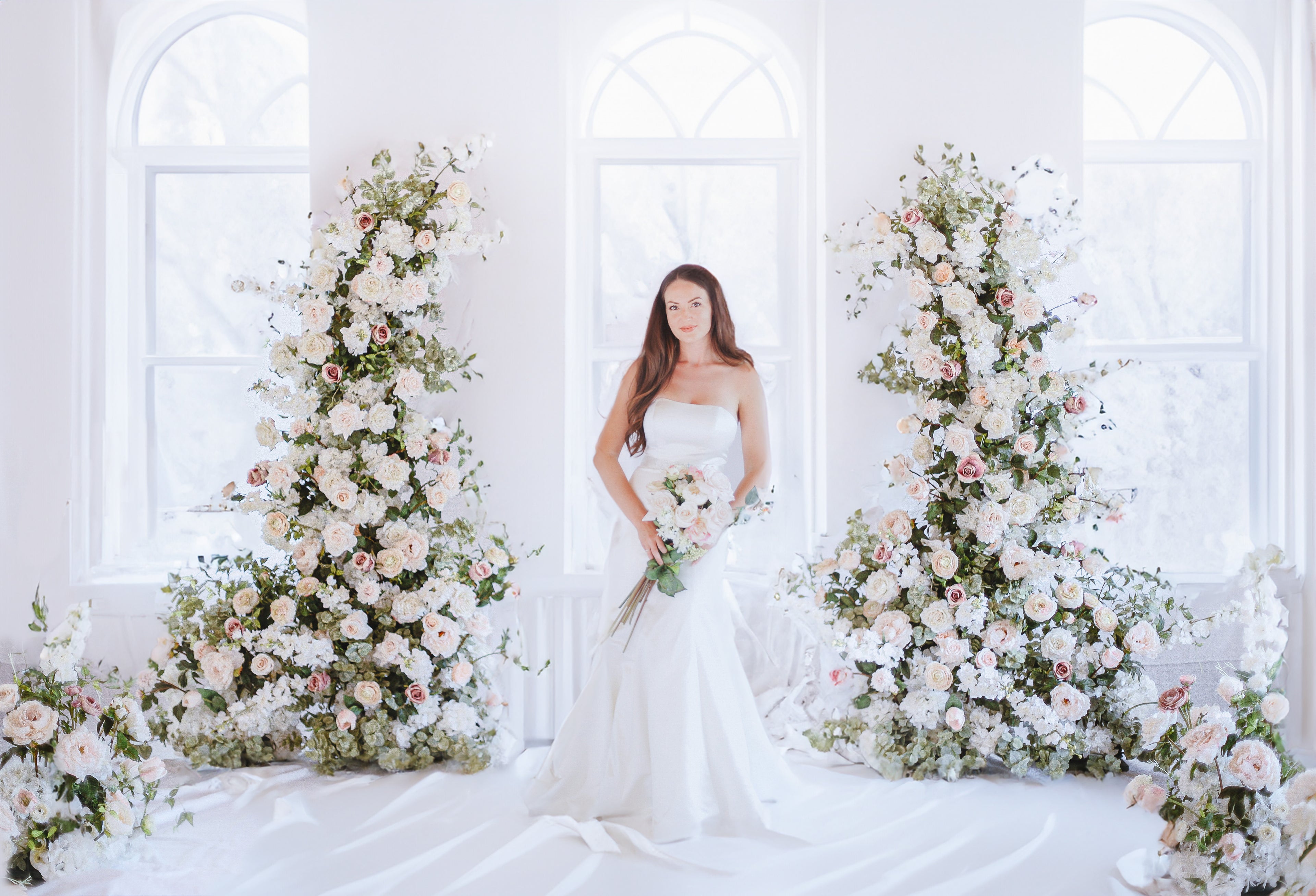 Bride under a wedding arch rental from Harmony Blossom Rentals.
