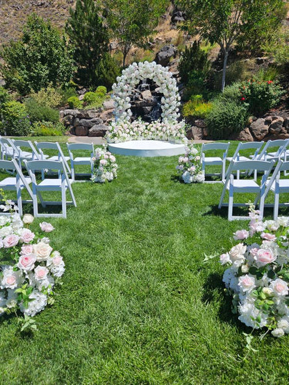 Outdoor wedding ceremony with luxury floral arch, aisle flowers, and platform.