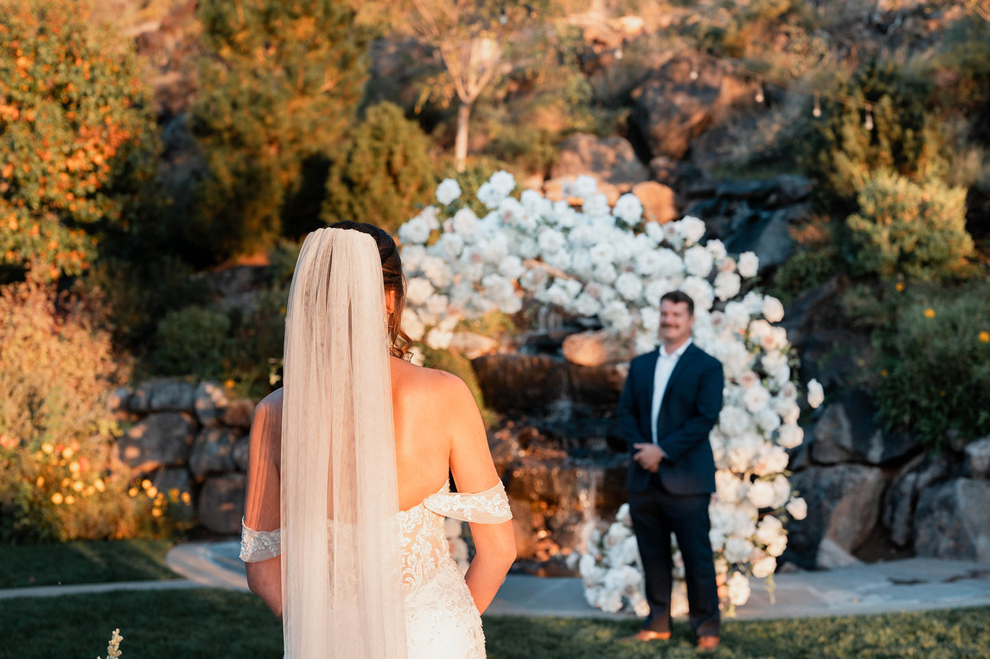 Wedding ceremony circle flower arch in white with hydrangeas roses peonies with bride and groom in the sunset