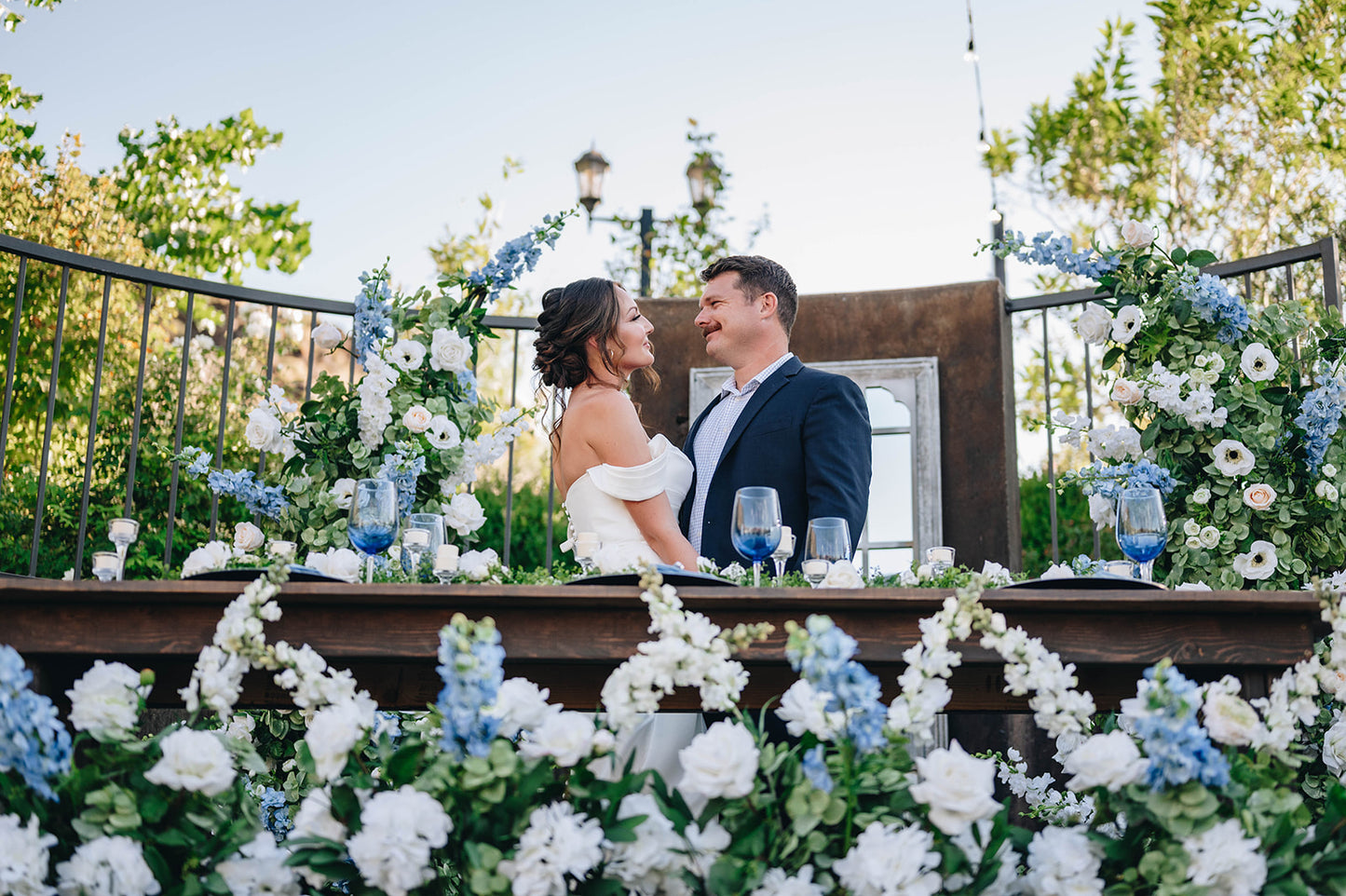 Bride and Groom smiling at each other surrounded by beautiful greenery flowers at reception smiling